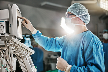 Image showing Surgery, machine and doctor with monitor in theatre for healthcare, cardiovascular operation or analysis. Medical professional, man and scrubs with equipment for cardiology, procedure or information