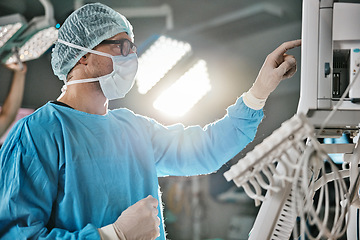 Image showing Surgery, machine and doctor with monitor in hospital for healthcare, theatre operation or analysis. Medical, man and surgeon in scrubs with digital technology for cardiology, procedure or information