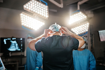 Image showing Medical preparation, cap and doctor in operating room for surgery, safety and clothes for protection. Healthcare, surgeon and theatre with uniform for emergency, procedure and operation in hospital