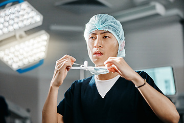 Image showing Medical, uniform and doctor in theatre for surgery, safety and preparation for operation in hospital. Asian man, surgeon and clothes with thinking for cardiology procedure, protection and healthcare
