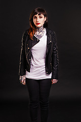 Image showing Portrait, tattoo and gothic woman in a leather jacket on a black background for edgy style in studio. Dark, unique and cool female punk model with ink on skin for art, fashion or creative expression