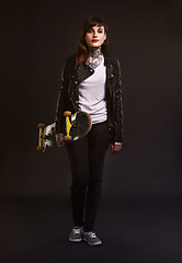 Image showing Studio, portrait and woman with skateboard in hand for fashion, punk clothes and grunge style. Skater, confidence and person with tattoos for satisfaction, rebel and gen z on black background