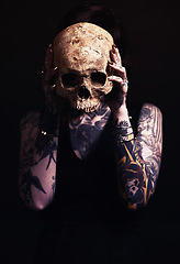 Image showing Skull, bone and woman with tattoo in studio for dark art, abstract horror or scary aesthetic with mask. Creative nightmare, halloween culture and unique person in surreal portrait on black background