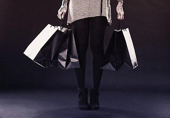 Image showing Woman, legs and shopping bags for fashion in studio on dark background with retail, discount and clothes. Female person, tattoo and edgy style with creative look, body ink and art for self care