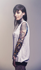 Image showing Portrait, tattoo and culture with woman, rebel and punk rock on a grey studio background. Heavy metal, artistic and model with confidence and proud with edgy person and trendy with ink and creativity