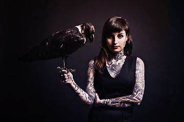 Image showing Fashion, woman and portrait with bird in studio for witchcraft or magic, mysterious and fantasy with punk tattoo. Person, eagle and isolated on black background for darkness and creepy grunge look.