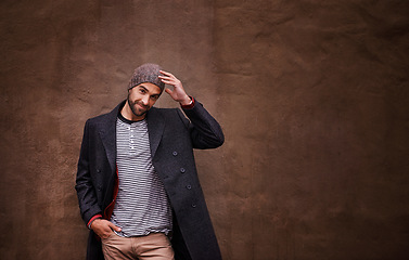 Image showing Man, confidence and smile with urban, fashion and trendy gentleman jacket. Model, winter and beanie with city, happiness or outdoor positivity for cool hipster style isolated on brown wall background