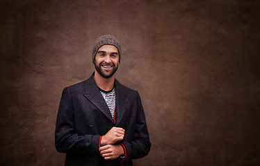 Image showing Man, portrait and smile with urban, fashion and trendy gentleman jacket. Model, winter and beanie with city, happiness and outdoor positivity for cool hipster style isolated on brown wall background
