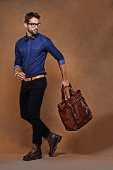 Image showing Travel, bag and man with fashion walking in studio, background and mockup for business vacation. Formal, style and model with luxury luggage for airport, journey to Italy and Italian leather shoes