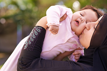 Image showing Muslim mother, outdoor and kiss baby for care, connection and bonding together in summer. Mom, kid and love on cheek for infant, adorable child and Islamic family at garden for healthy relationship