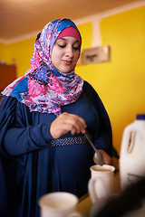 Image showing Muslim woman, mug and making coffee in kitchen for morning enjoyment, warm drink and preparation. Female person, cup and beverage with milk for routine, start day or caffeine satisfaction at home