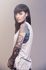 Image showing Portrait, culture and woman with tattoos, confidence and punk rock on a grey studio background. Face, person and model with creativity or artistic with rebel and gothic with expression, casual or ink