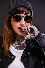 Image showing Sunglasses, tattoo or woman in studio for fashion in leather jacket on black background for edgy style. Dark, bold or cool female punk model with ink for unique art, aesthetic or creative expression