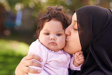 Image showing Muslim woman, mother and baby kissing for love, care and bonding during Eid in Cape Town, South Africa. Female person, child and family together outdoor in nature, garden and backyard with affection