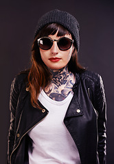 Image showing Sunglasses, tattoo and woman in studio in a jacket on a black background for edgy style or aesthetic. Dark, leather and cool female punk model with ink for unique art, fashion or creative expression