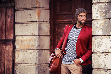 Image showing Man, fashion and model in city with confidence, trendy style or winter accessories with bag outdoor. Urban, unique and stylish with designer clothes, edgy and chic with wool hat or beanie for weather