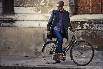 Image showing Bicycle, stylish and man in city for travel on winter vacation, adventure or holiday with retro style. Vintage, fashion and male person on bike for cycling with beanie and coat for outfit in town.