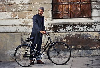 Image showing Bicycle, fashion and man in city for travel on winter vacation, adventure or holiday with retro style. Vintage, stylish and male person on bike for cycling with beanie and coat for outfit in town.