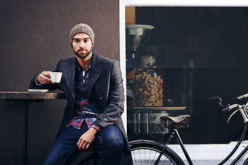 Image showing Portrait, city and man drinking coffee with bicycle at cafe table for breakfast in the morning. Bike, tea cup and serious person with espresso, latte or beverage at restaurant with winter fashion
