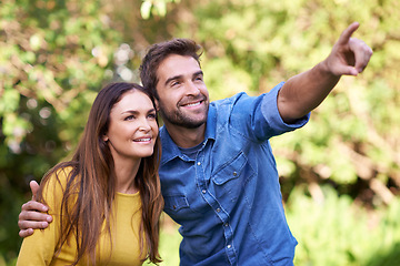 Image showing Happy couple, women and man pointing in nature or park for bonding, dating and relationship with smile. People, love and romantic in backyard or outdoor with joy, excited and commitment in marriage