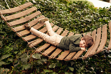 Image showing Kid, boy and happy with lying on hammock outdoor for fun to play, child development and growth. Children, holiday and tree with smile for joy to sing on summer vacation or break for leisure at home