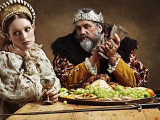 Image showing King, queen and portrait with feast at table for fine dinning in royal banquet, vintage and majestic with crown. Monarch, husband and bored together with alcohol for buffet for formal celebration.