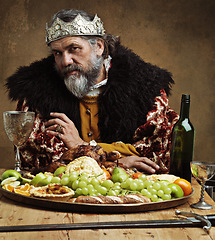 Image showing King, confident and feast in table with wine as royalty on dining hall for tradition, culture and meal in palace. Portrait, monarch and leader with eating buffet or supper with sword for chicken