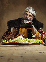 Image showing King, royal and feast in table with wine as lord on dining hall for tradition, culture and meal in palace. Portrait, monarch and food with man eating buffet or supper with confidence and crown