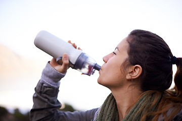 Image showing Woman, hiking and outdoor to drink with bottle, water and hydration for health, fitness and adventure. Girl, person and trekking in bush, mountains and rocks for electrolytes on journey in Cape Town