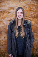 Image showing Nature, rock and portrait of woman with smile, relax and standing outdoor of cave in environment. Adult, girl and female person with joy and happiness to explore or travel for holiday in winter