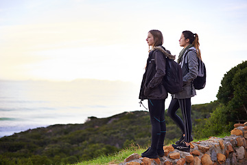 Image showing Outdoor, hiking and friends in nature with backpack, sightseeing and standing to relax on rock. Women, girl and female person on vacation for break or holiday in peace of forest and journey