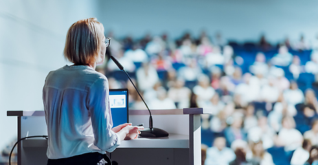 Image showing Female speaker giving a talk on corporate business conference. Unrecognizable people in audience at conference hall. Business and Entrepreneurship event.