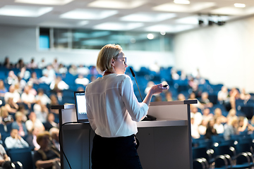 Image showing Female speaker giving a talk on corporate business conference. Unrecognizable people in audience at conference hall. Business and Entrepreneurship event.