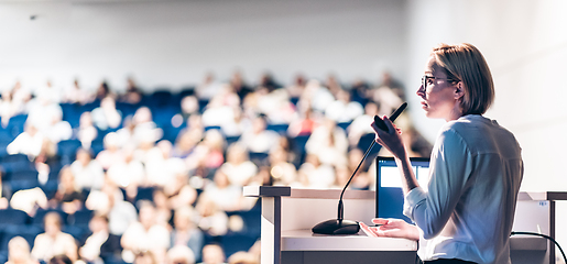 Image showing Female speaker giving a talk on corporate business conference. Unrecognizable people in audience at conference hall. Business and Entrepreneurship event.