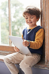 Image showing Home, tablet and happy kid on internet, app or game on website for learning by windowsill. Technology, smile and child in house for education, scroll and watch cartoon online on digital electronics