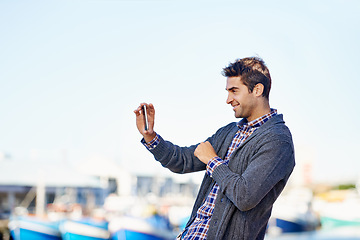 Image showing Man, smartphone and photography at harbor, outdoor and smile by ocean with creativity for web blog. Person, photographer and phone for profile picture, social media or memory by sea port in Cape Town