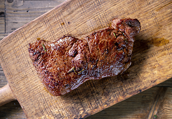 Image showing fresh grilled beef steak meat with salt and pepper on wooden cut