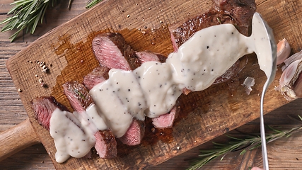 Image showing Chef pours pepper sauce on a slices of freshly grilled beef stea