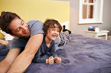 Image showing Happy, playing and father with child on bed bonding, relaxing and having fun together at modern home. Laughing, smile and young dad laying with boy kid in bedroom on weekend at family house in Canada