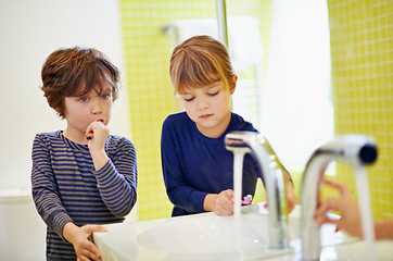 Image showing Siblings, learning or children in home brushing teeth together for development in morning or bathroom. Boy, girl or kids cleaning mouth with tap or toothbrush for dental or oral health for wellness