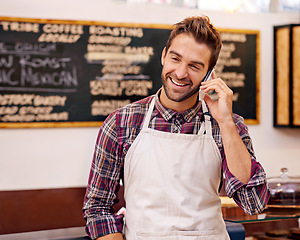 Image showing Man, waiter and happy for phone call in a coffee shop to talk to contact for drink order at small business. Person, barista and smartphone for listening to chat, networking and smile in a cafeteria