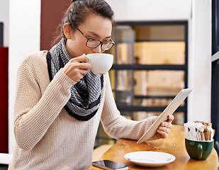 Image showing Woman, drinking coffee and tablet in cafe with freelancer work and social media with cappuccino. Website, drink and internet with digital blog writer and technology at restaurant with tea and reading