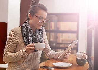 Image showing Woman, coffee shop and tablet with freelancer research and social media in cafe with cappuccino. Website, drink and internet with digital blog writer and technology at restaurant with tea and reading