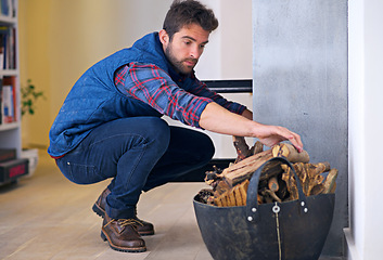 Image showing Fireplace, wood and man in home for fire preparation for heat, warmth and light in winter. Flame, burning and person with firewood or logs for comfortable, cozy and relaxing atmosphere in living room