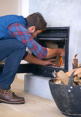 Image showing Fireplace, wood and man ignite fire for heat, warmth and light in winter in home. Flame, burning and person with firewood or logs for comfortable, cozy and relax for thermal heating in living room