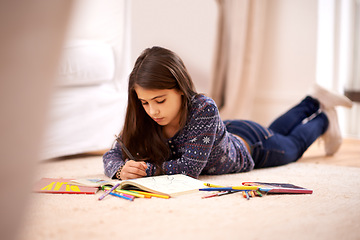 Image showing Girl, coloring book and pencil on floor for sketch in home for learning, development or drawing in lounge. Kid, art and education for studying, creativity or relax on carpet at family house in Madrid