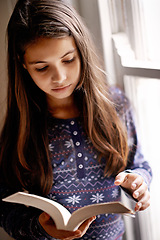 Image showing Girl, child and book for reading in home with thinking, learning and language by window for studying. Kid, literacy and ideas with story, novel and fantasy with education in family house in Madrid