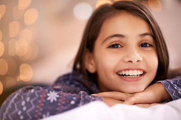 Image showing Home, happy and portrait of child on bed for relaxing, resting and smile in bedroom at night. Youth, blanket and face of young girl with fairy lights for childhood memory, peace and happiness