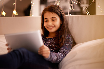 Image showing Girl, kid and tablet, happy with tech and relax on sofa with ebook for reading and social media at home. Elearning, cartoon or storytelling app with internet, browsing and digital platform for gaming