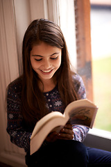 Image showing Girl, kid and book with smile in home for reading, learning and language by window for studying. Child, literacy and thinking with story, happy and fantasy with education in family house in Madrid